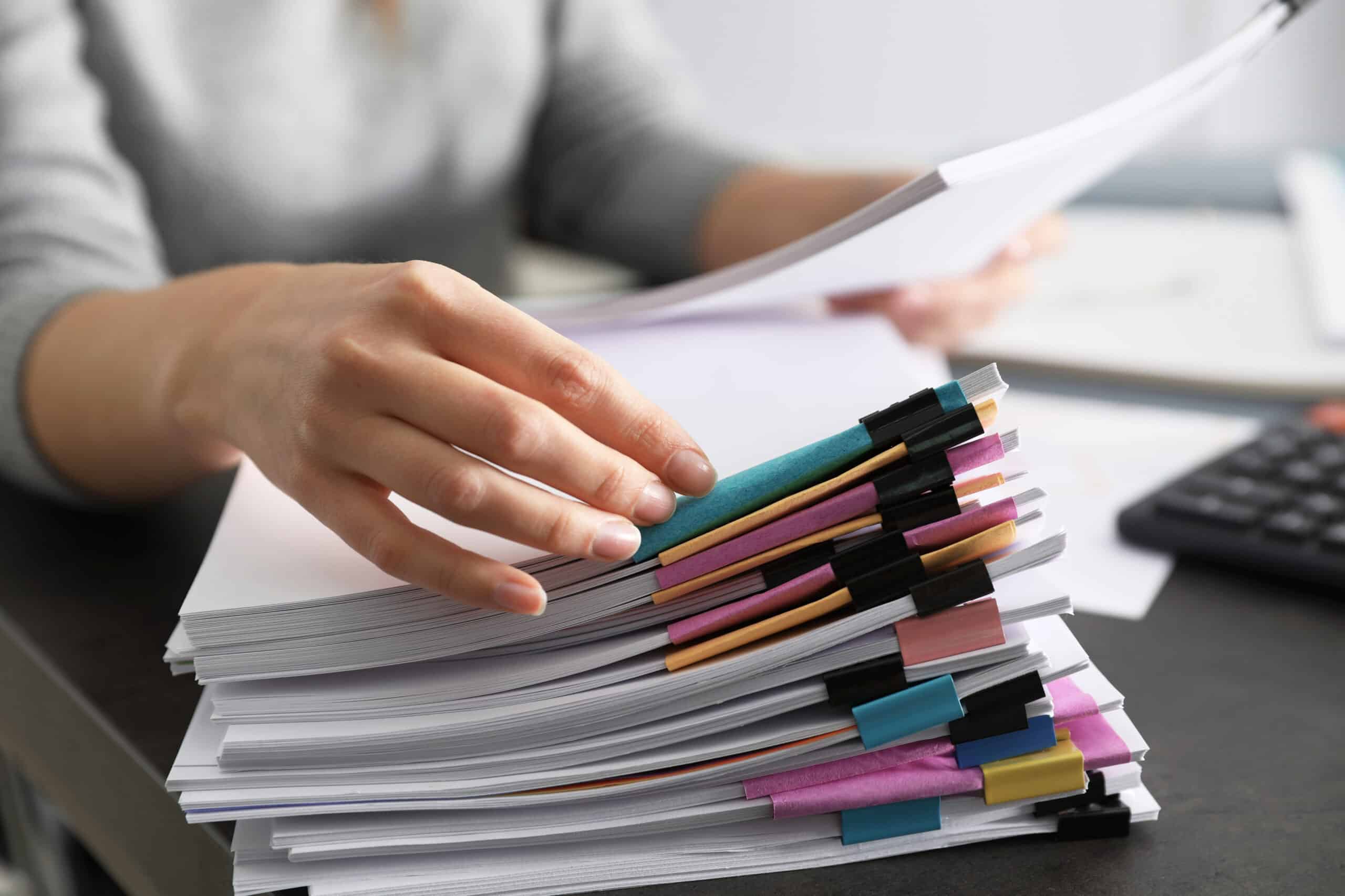 Person sorting through documents at table, closeup