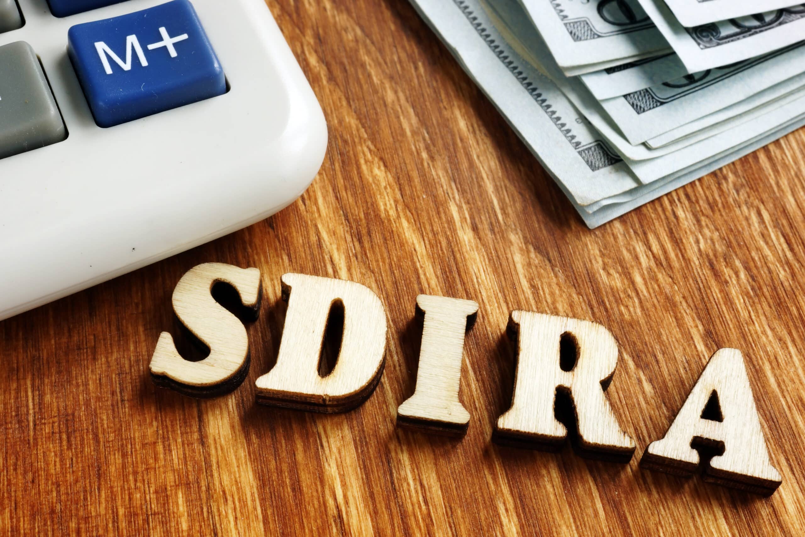 Self Directed IRA, SDIRA wooden letters on desk.