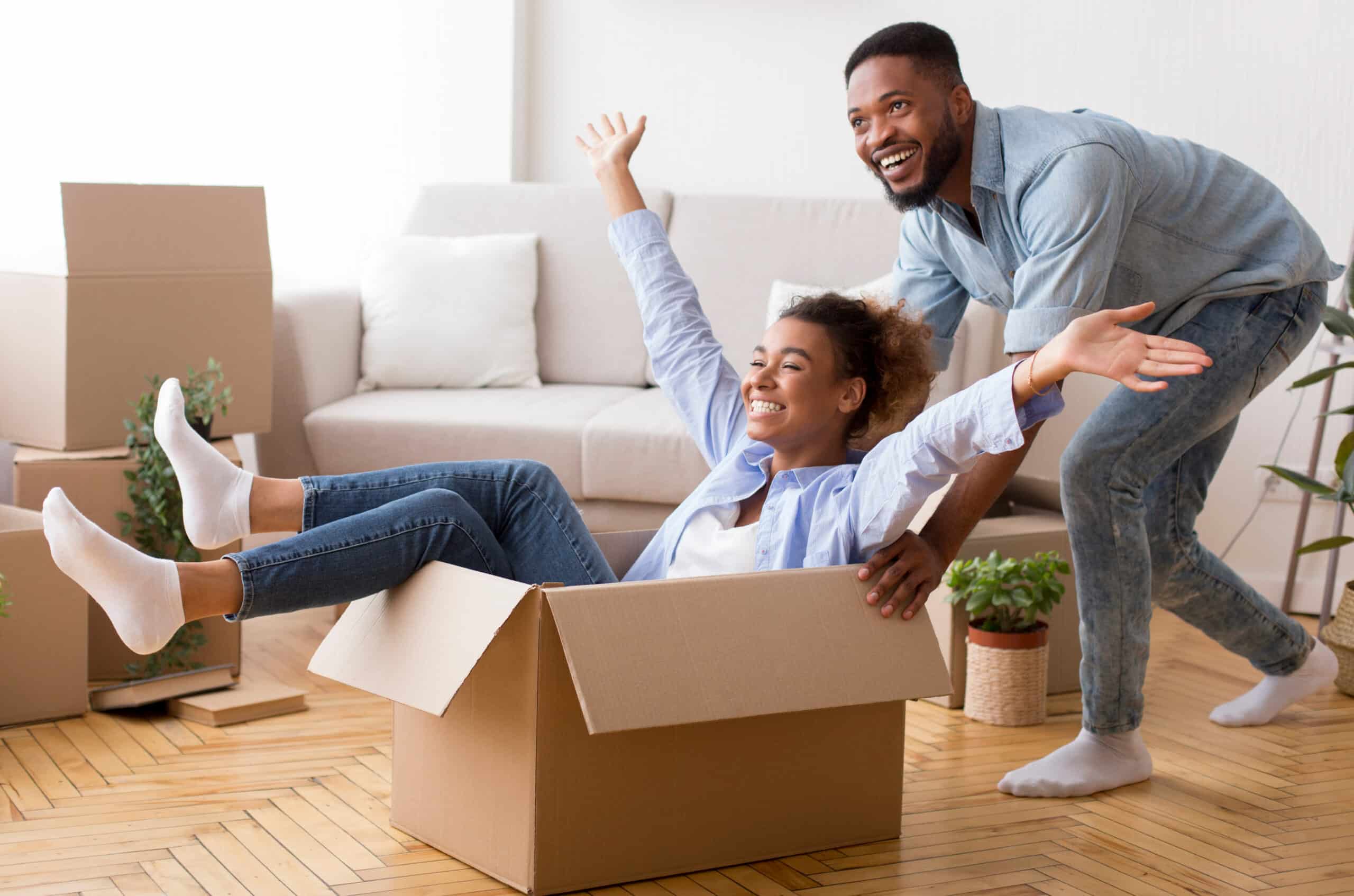 Home purchase, home loans, mortgage lending, first time homebuyer, mortgage programs, Texas mortgage, community lender, Afro Husband Riding Wife In Moving Box In New House